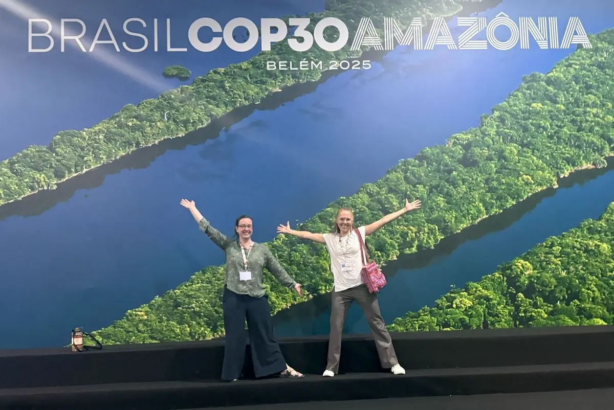 New Joy Winbourne and Jasmina Burek pose under a COP 30 sign.