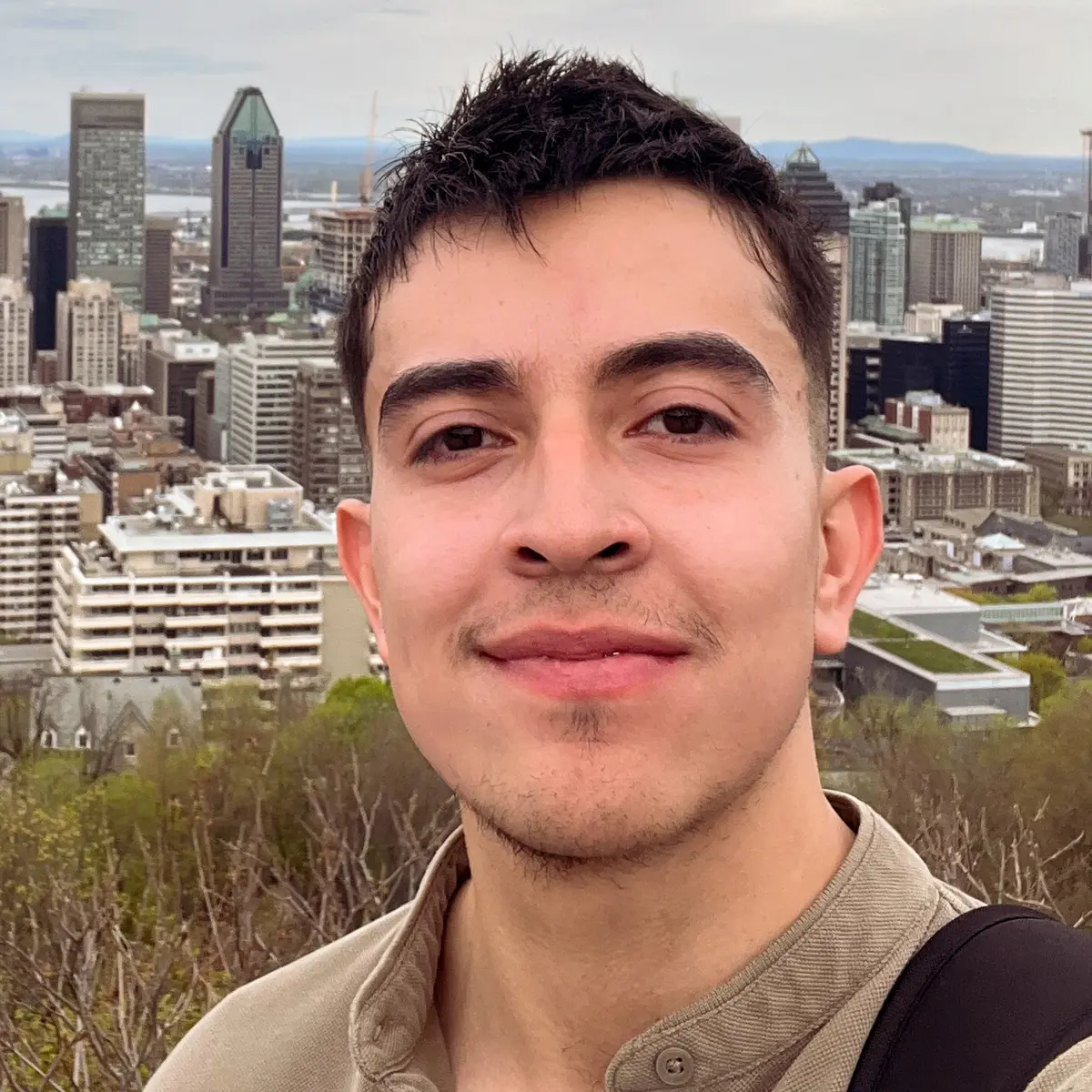 A young man poses for a photo while overlooking a city.