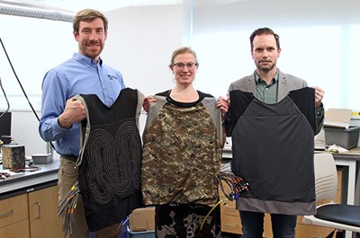 Professors holding cooling vests designed for military use.