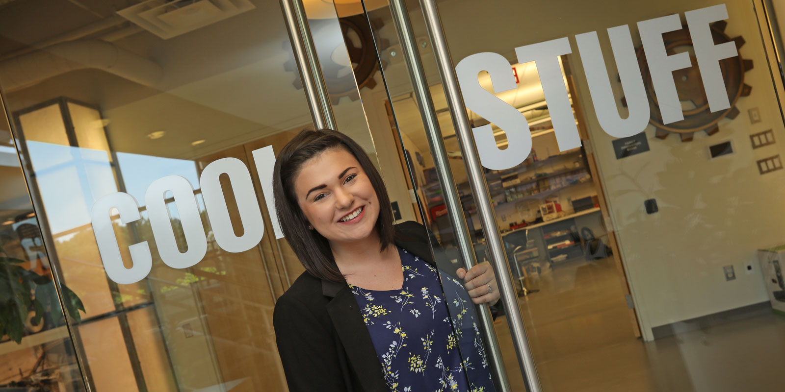 Co-op student opening glass doors with words cool stuff