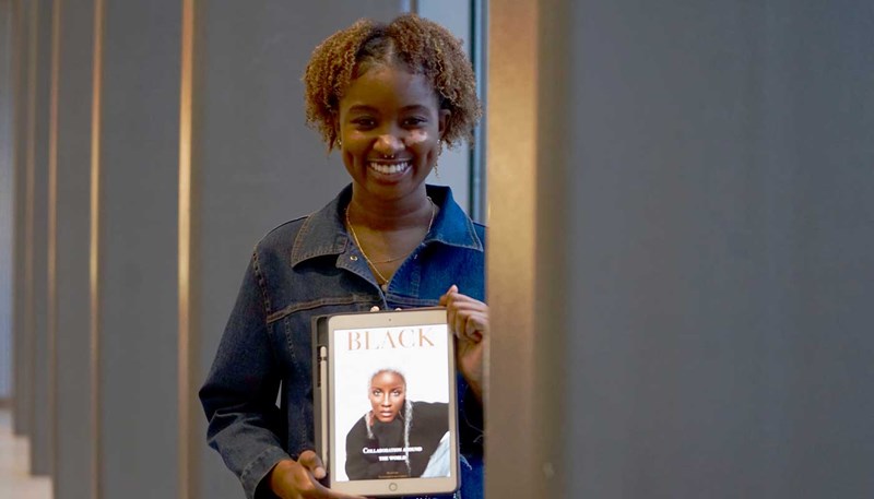 UMass Lowell business student Kristin Kihara holds a tablet displaying the cover of her magazine Black.
