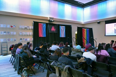 Image of a crowd sitting in seats at the LGBTQ Center
