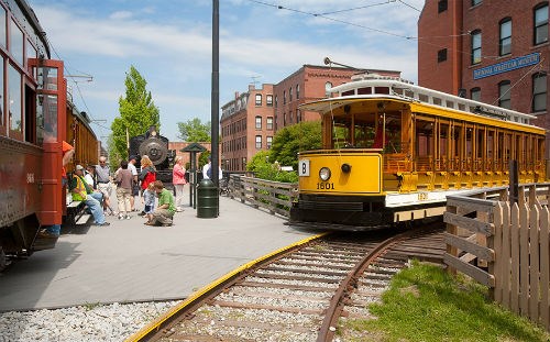 Park visitors wait as a yellow trolley tour arrives in Lowell