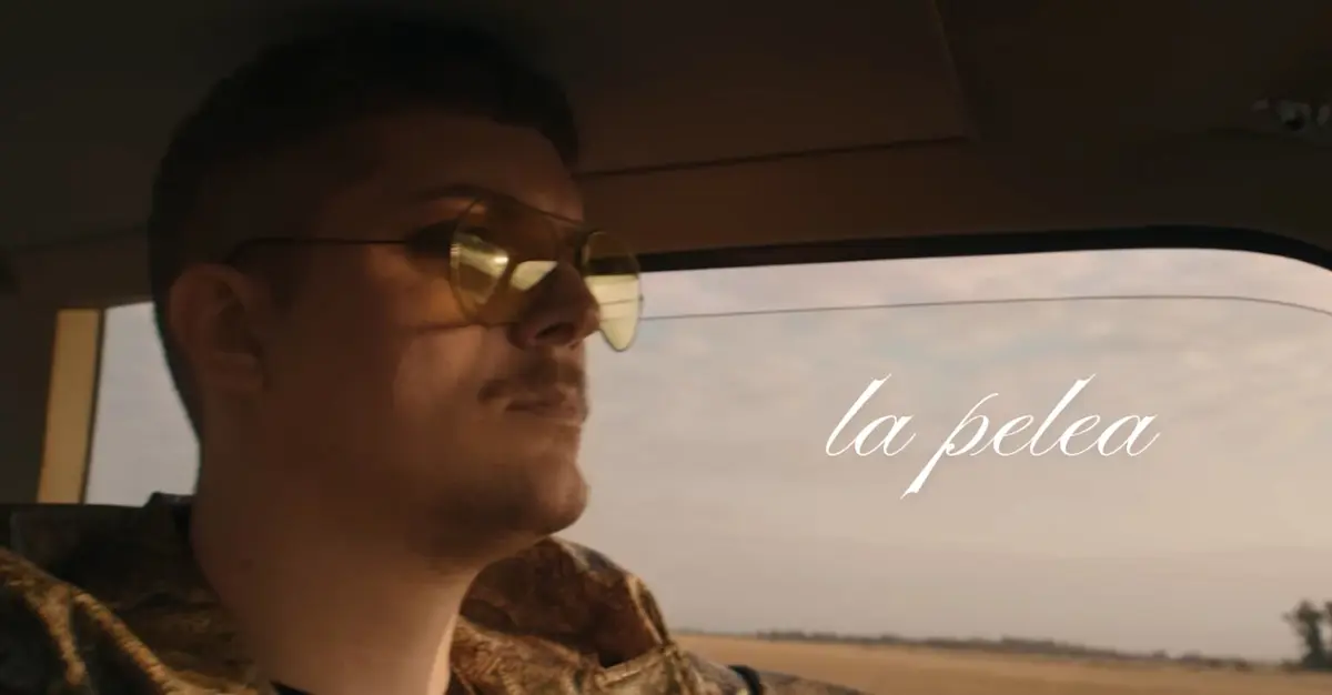 Person in sunglasses sitting in a car, staring forward. Text reads: "la pelea."