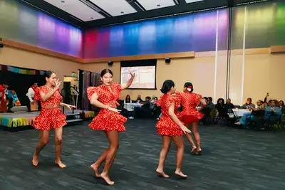 Latin dancers dressed in red dance in a circle at an event.