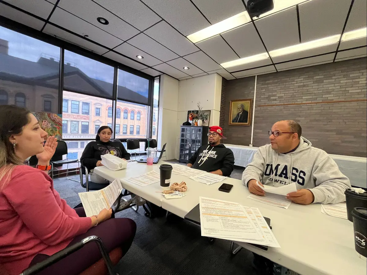 Four people sit around a table discussing documents on the table