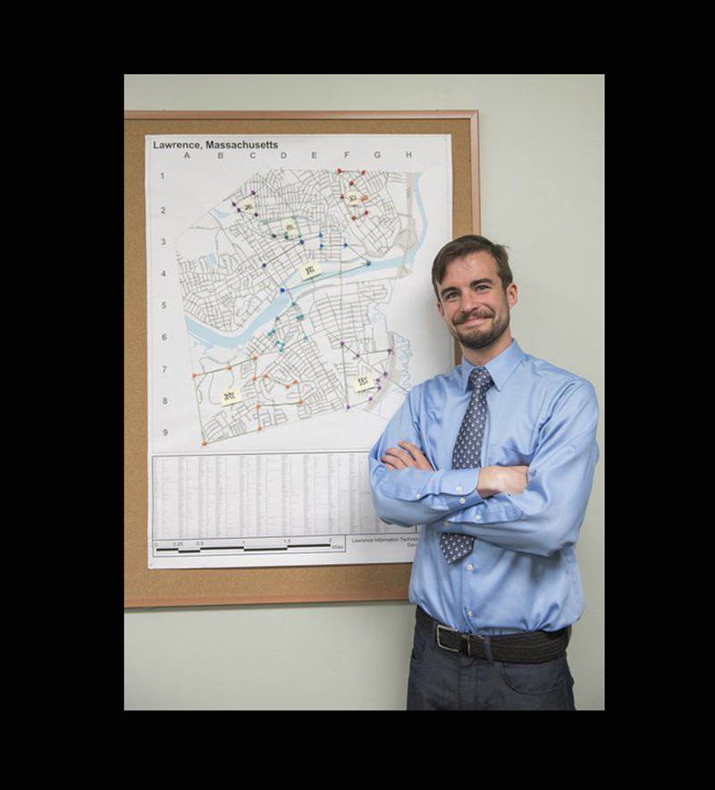 Liam Fouhy posing in front of a map of Lawrence. Image used courtesy the Eagle Tribune and Amanda Sabga.