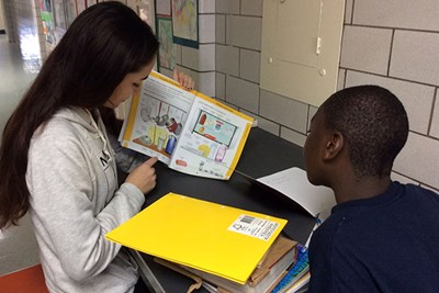 Lily Gillette helps a student learn English from a picture book.