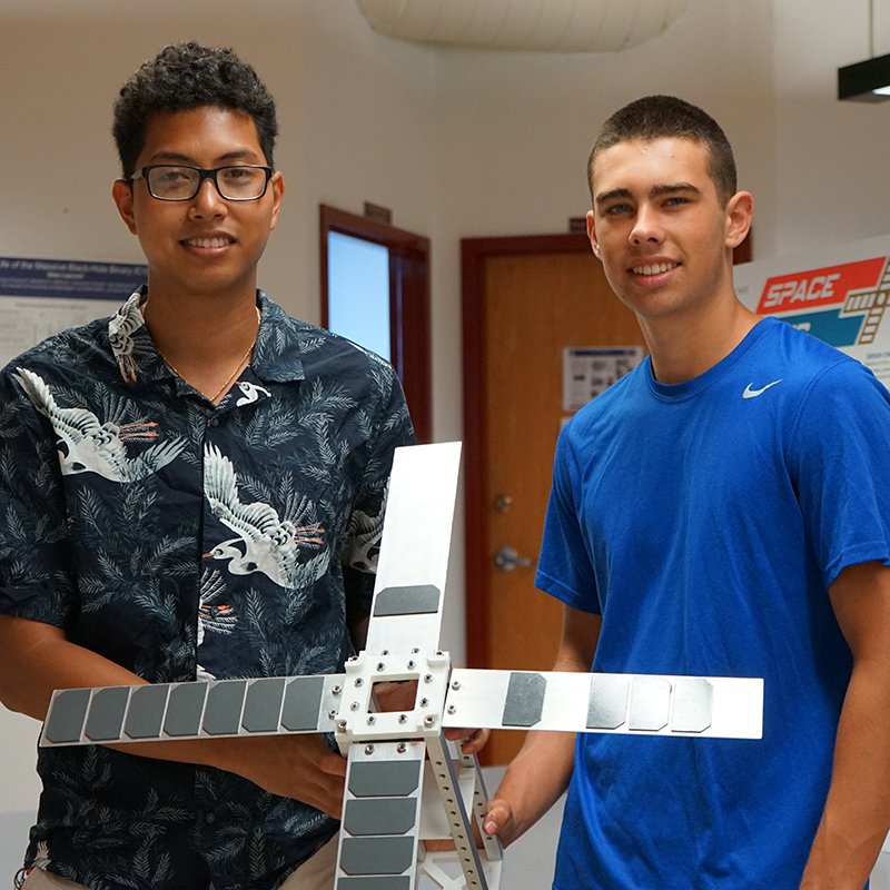 Liono and Matt, mechanical engineering students at the Lowell Center for Space Science and Technology with the CubeSat satellite