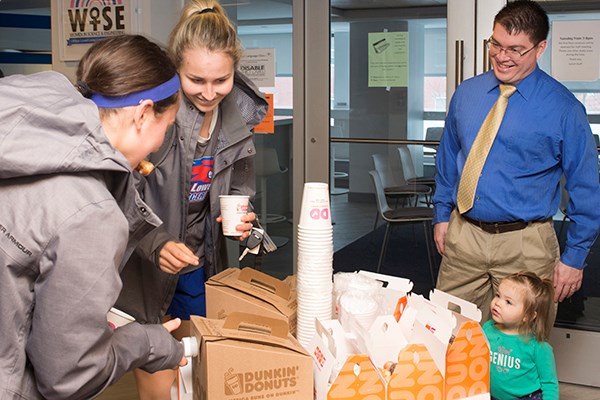 Faculty adviser David Adams and his daughter offer coffee and donuts to freshmen in the Honors LLC.