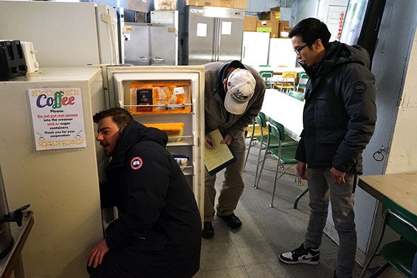 Orhan Kallogjeri inspects a refrigerator while Tu Anh Huynh looks on