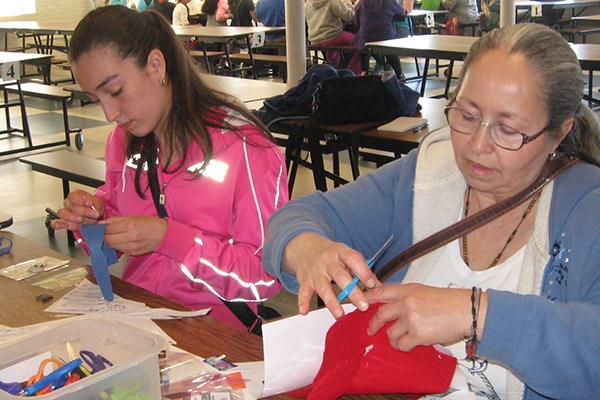Students sewing circuit bracelets with steel thread at a LNHP class