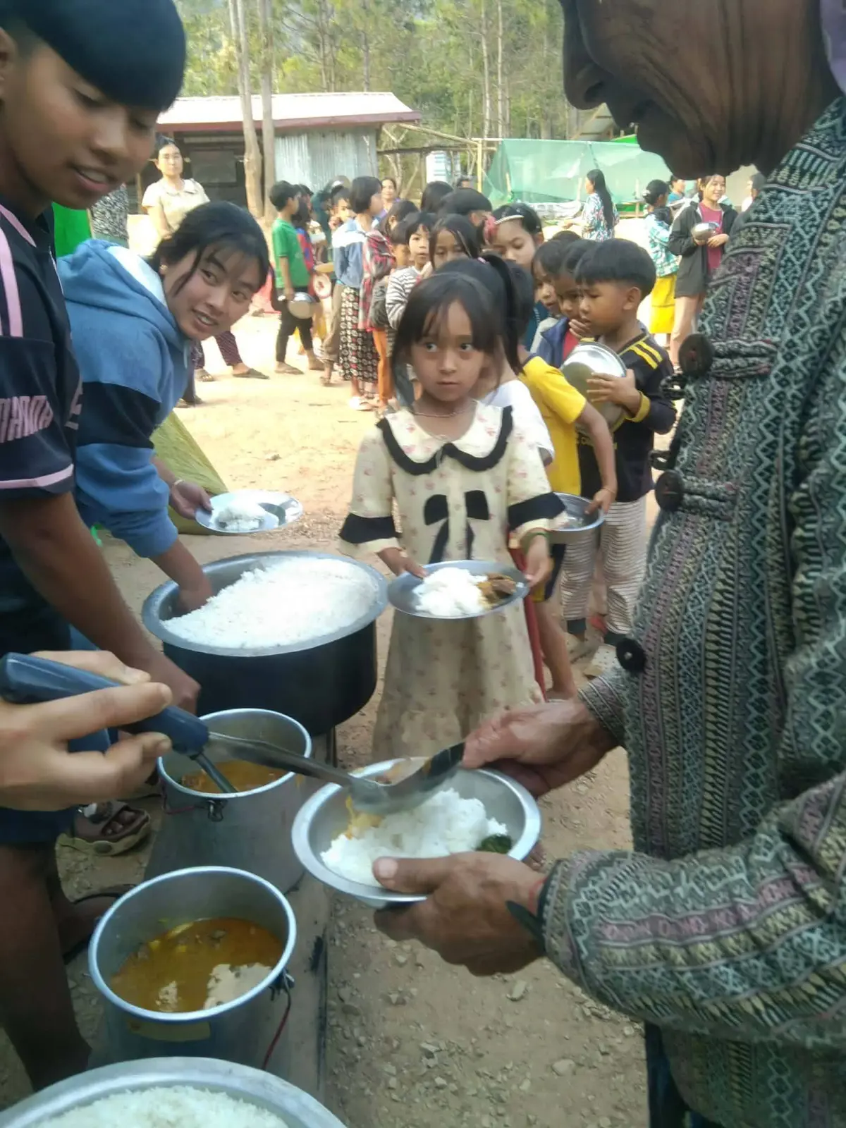 Internally displaced children line up for food at a temporary school in Myanmar