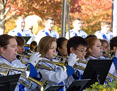 The Umass Lowell band group performing outside a field on Umass Lowell.