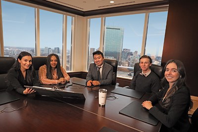 Five co-op students sit at a conference table in an office building