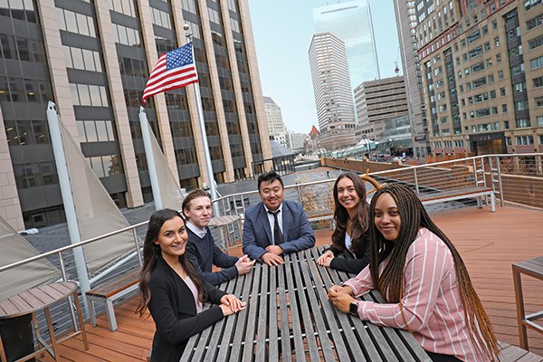 Five co-op students sit around a table on an outdoor deck in downtown Boston