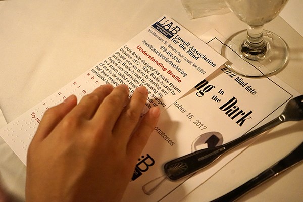 A student touches a Braille alphabet card