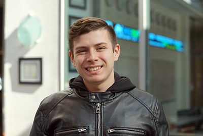 A student with short dark hair smiles while posing for a picture 