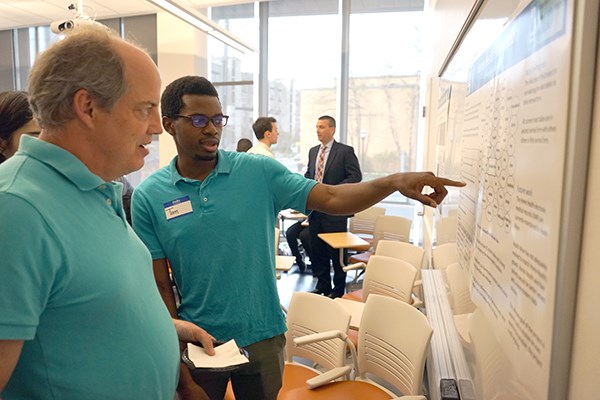 An MSBA grad student explains his project to a guest at the capstone presentation ceremony