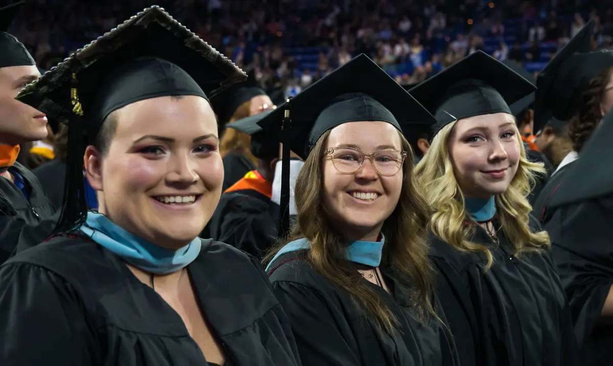 Three students at graduation in caps and gowns
