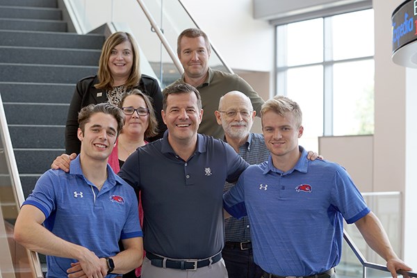 Ludwig Marek poses with two UML hockey players and four faculty and staff members