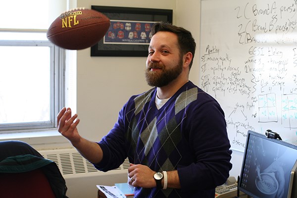 Asst. Prof. Spencer Ross tosses a football in his office