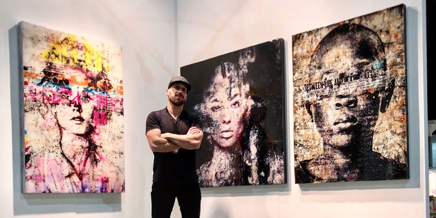 Markus Sebastiano stands in a gallery in front of three of his pieces