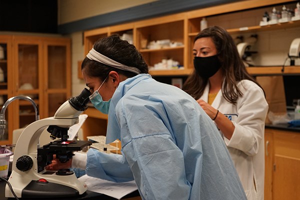 UML Clinical Asst. Prof. Jennifer Nicoloro, director of the Medical Laboratory Science Program, talks to student Evelin Ferreira as she inspects a slide
