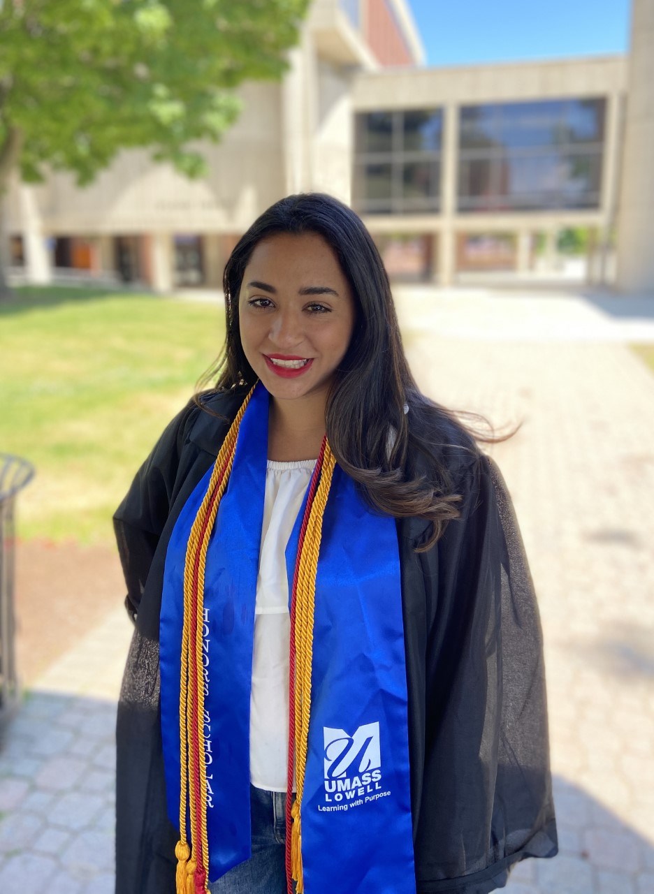 Headshot of Melissa DiPano in cap and gown outside in front of O'Leary Library on UML's South Campus.