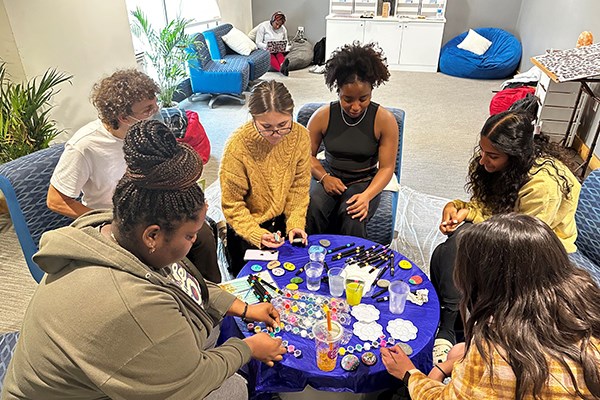 Students paint kindness rocks in the Serenity Center on a Wellness Wednesday organized by graduate intern Shakira Fedna, who is sitting next to assistant director of student life and wellbeing Hannah Monbleau