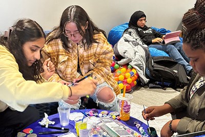 Nidi Patel, Valentina Munoz and Gloria Pierre paint kindness rocks in the Serenity Center while Doa Jamal studies