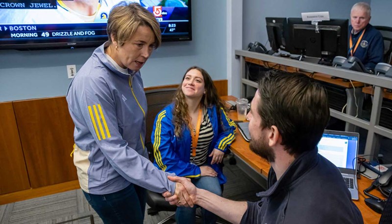 UMass Lowell alumnus Michael Souza shakes the hand of Governor Maura Healey while another student looks on.