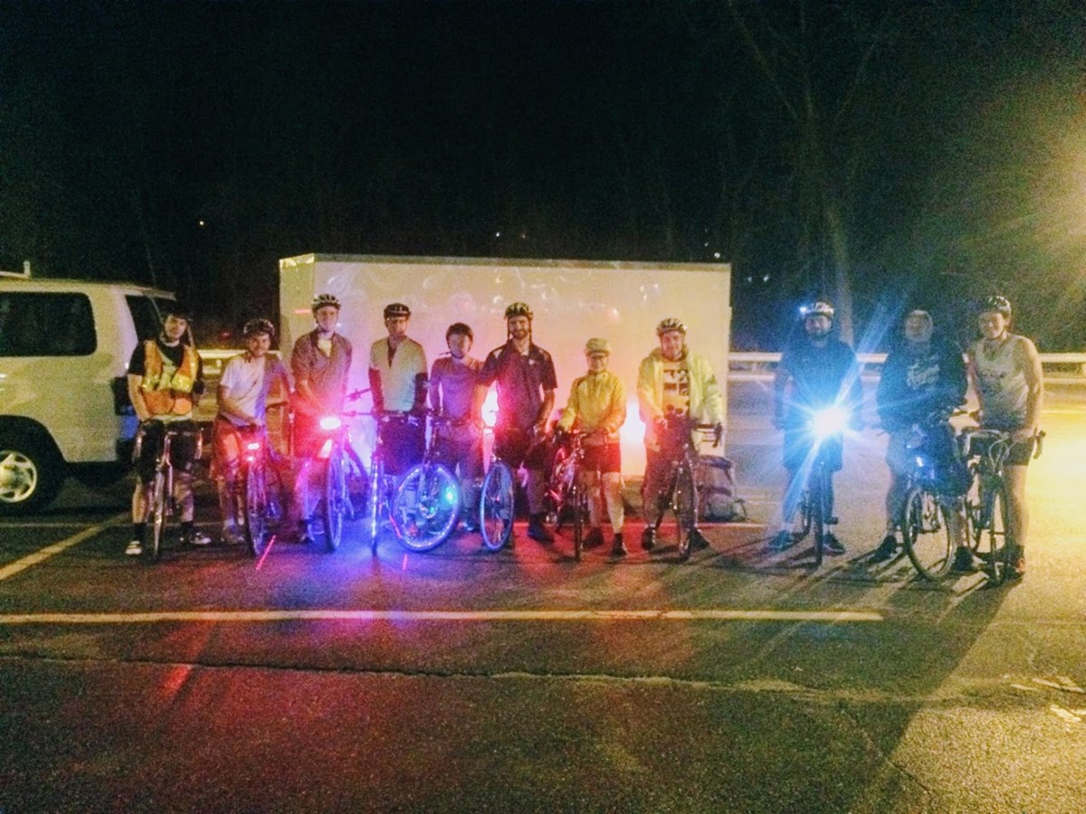 Cyclists lined up with bright safety gear on a dark night.