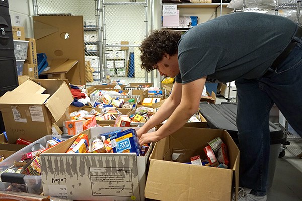 Student Christian Franco sorts donations to the Food Pantry