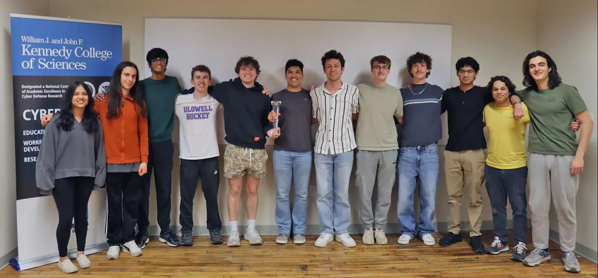 Twelve students pose with a trophy.