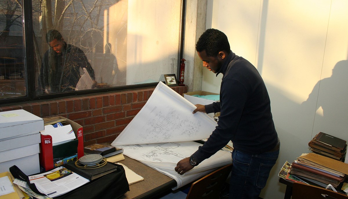 Electrical engineering student Mickyas Yihdego holding blueprints