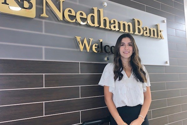 Nadine Chamoun standing in front of Needham Bank signage