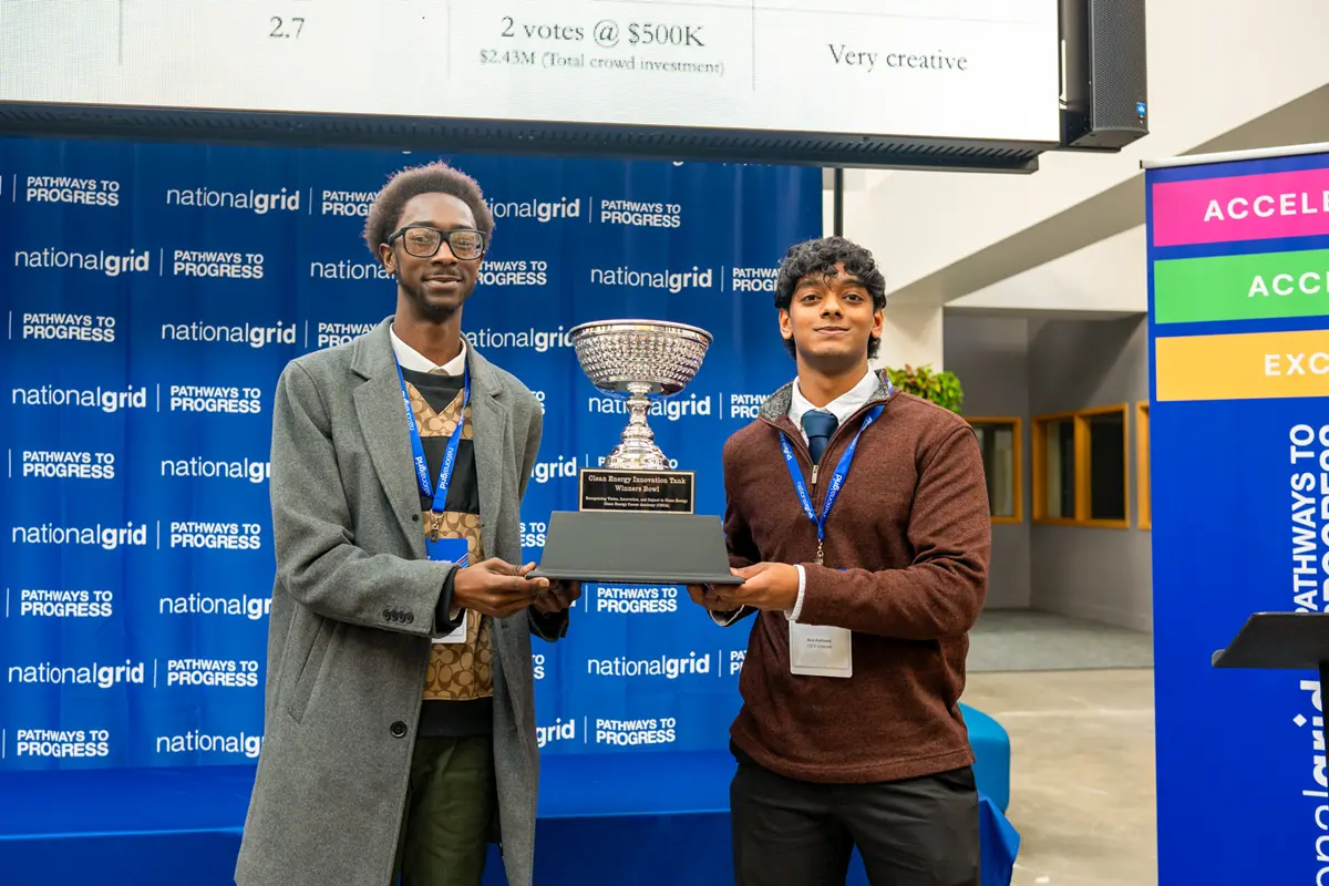 Two students hold a trophy at a National Grid event.