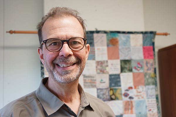 UMass Lowell College of Education Assoc. Prof. James Nehring in his office, with a quilty made by families of his former students