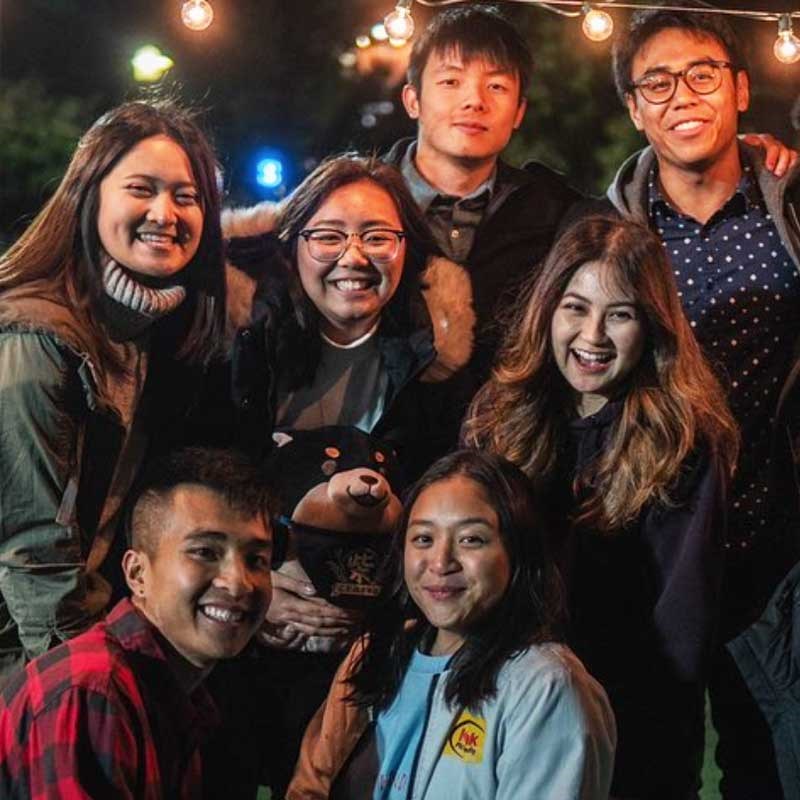 A group of students from the Vietnamese Student Association (VSA), a UMass Lowell cultural student organization, pose in an outdoor night market. 