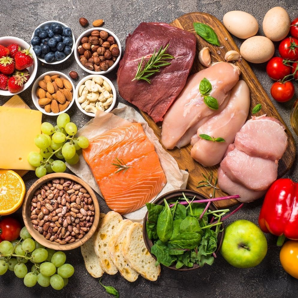 A variety of nutritional foods including fresh meats and poultry, fruits, vegetables, grains, bread, nuts, legumes, eggs and olive oil.
