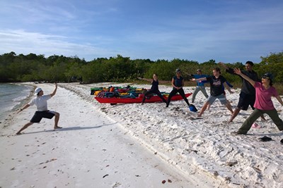 Students do morning yoga on the beach