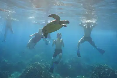 Ten people pose for a group photo while sitting on a boat with the sun setting behind them.