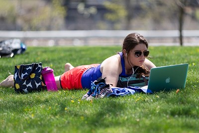 UMass Lowell student studies on the South Campus lawn
