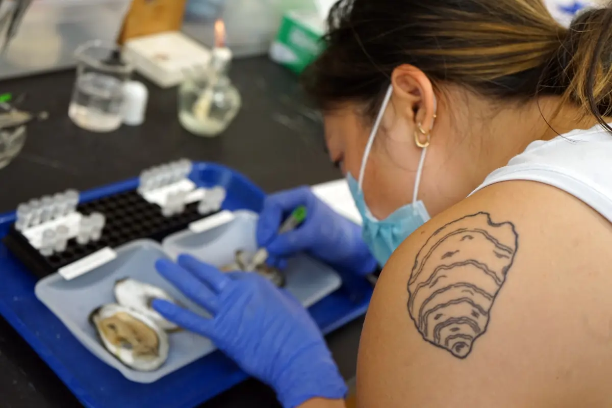 Two men and five women stand and pose for a photo in a science lab.