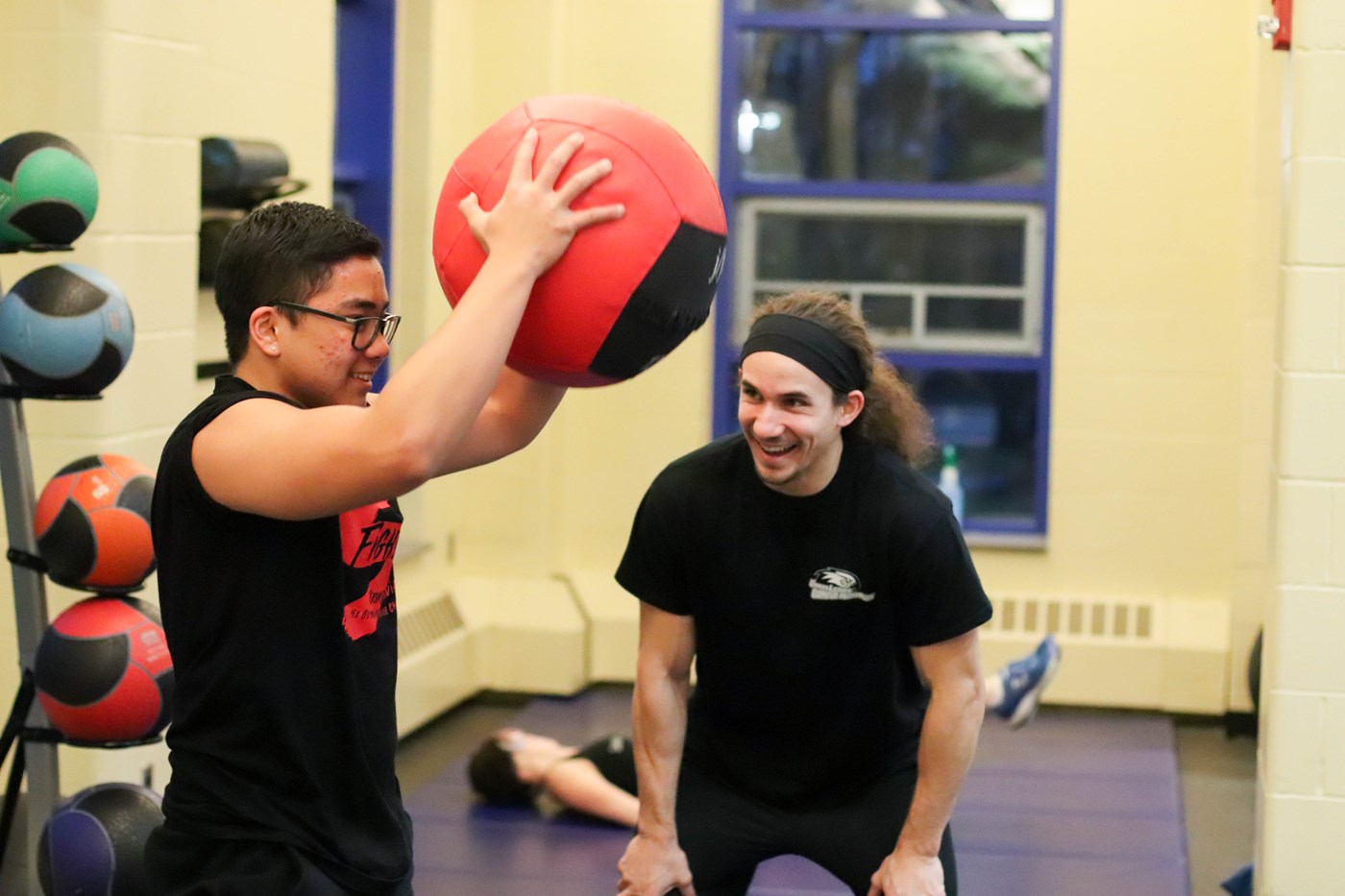 Personal Trainer cheering on student client doing a medicine ball slam