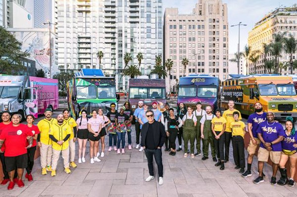 Contestants on The Great Food Truck Race TV show pose for a photo with the host in a city plaza