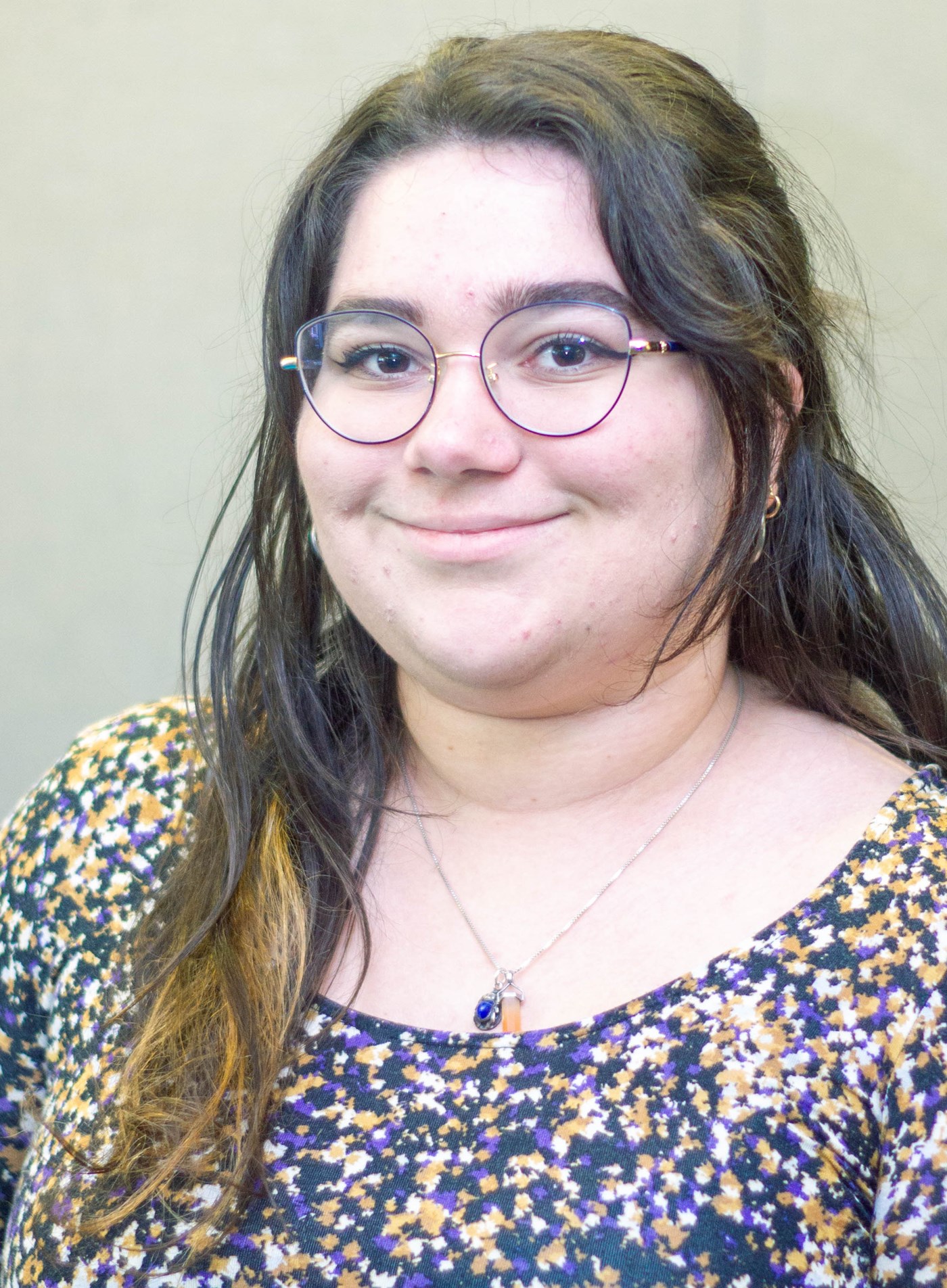 Hannah Patrignani wearing glasses and a necklace and smiling at the camera.