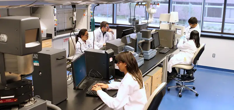 People in lab coats working on computers in a lab