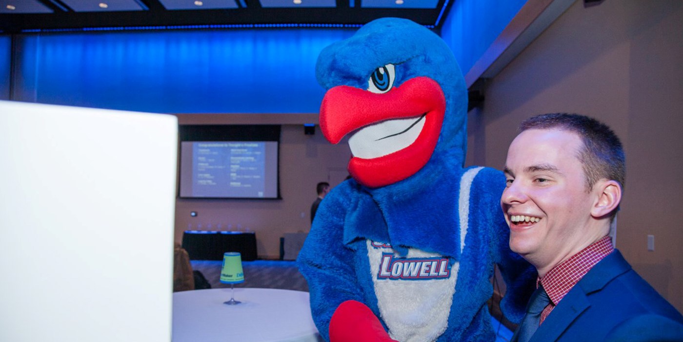Daniel Falcone shakes hands with Rowdy the River Hawk